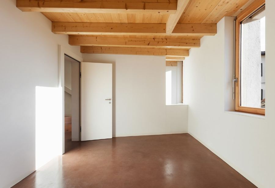 Estancia vacía con vigas de madera y suelo de terracota tras el vaciado — Cuánto se tarda en vaciar un piso